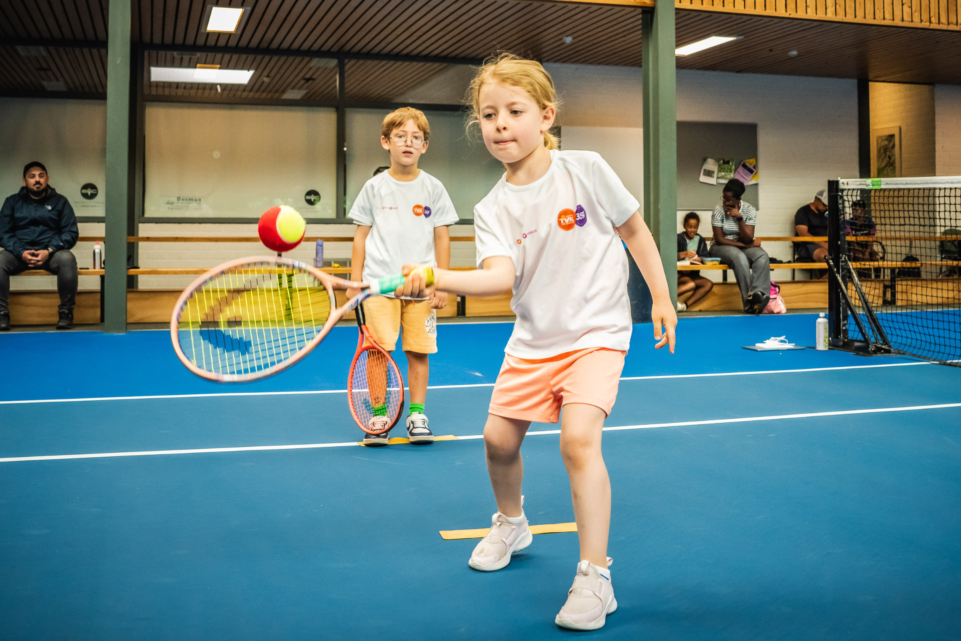 Meisje slaat forehand met rode bal indoor — 359.tennis, NTC Amstelveen