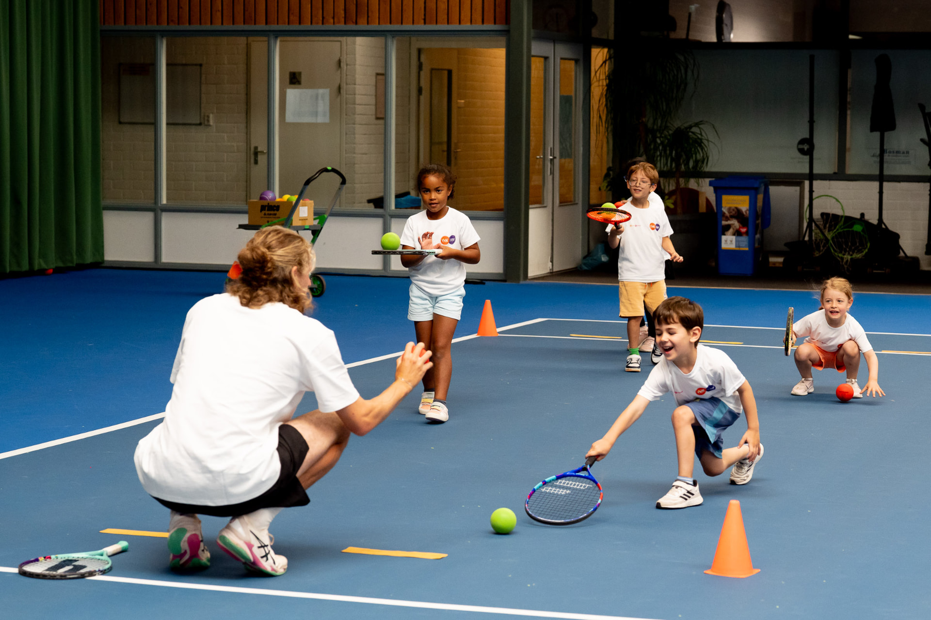Coach tossing a ball during a tennis kids lesson — 359.tennis, NTC Amstelveen