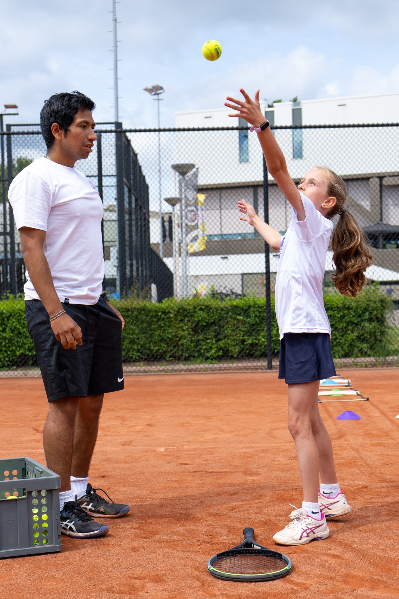 Coach begeleidt jonge speler bij opgooi voor service — privéles kids 359.tennis