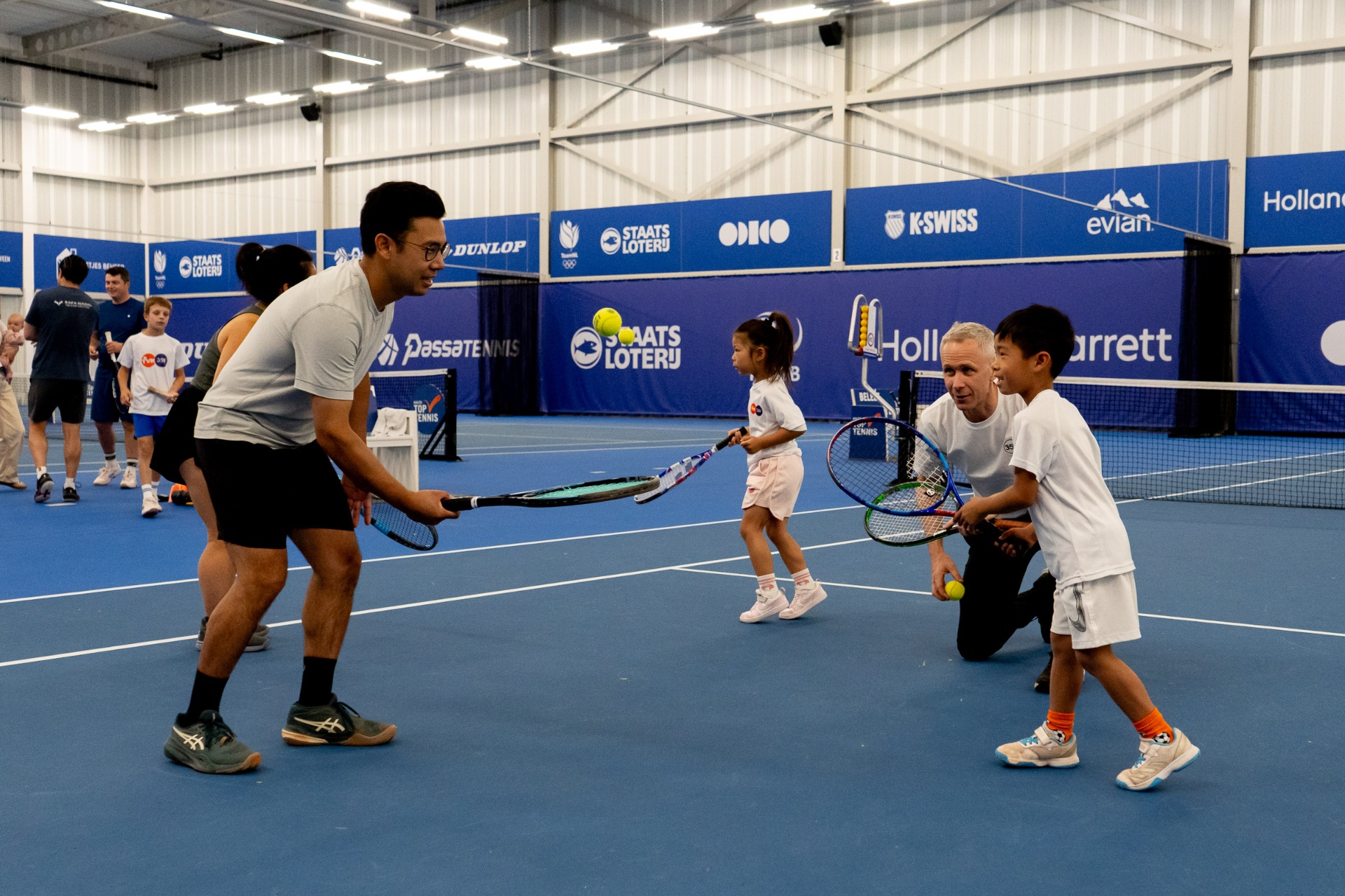 Indoor familietennis: coach helpt jong kind met het racket