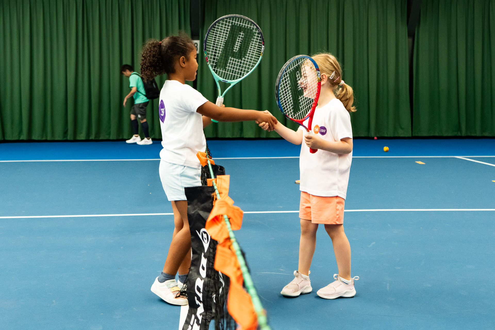 Two children shake hands after an indoor tennis lesson at TV De Kegel Amstelveen — 359.tennis