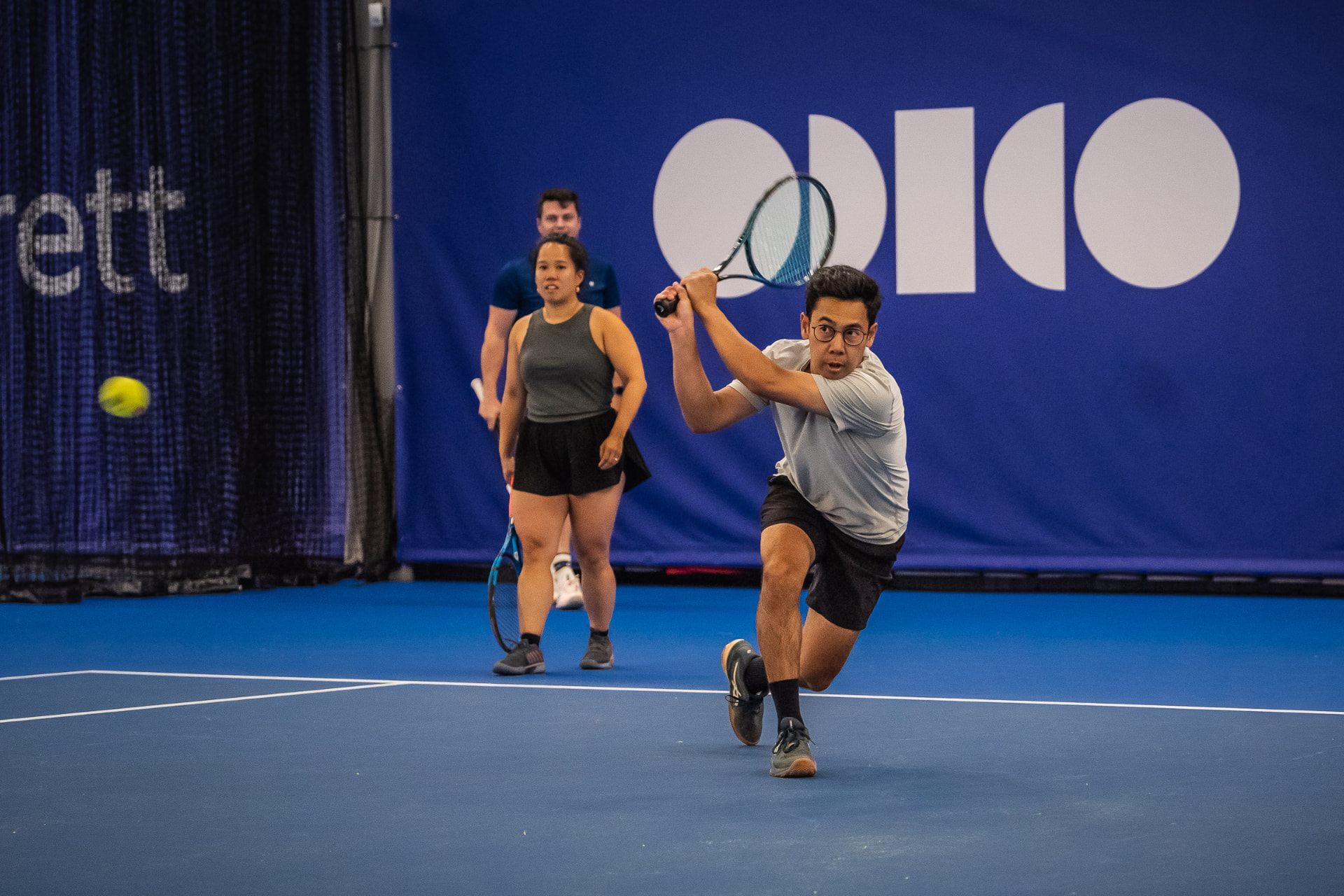 Volwassen speler slaat backhand tijdens dubbeltraining indoor — 359.tennis