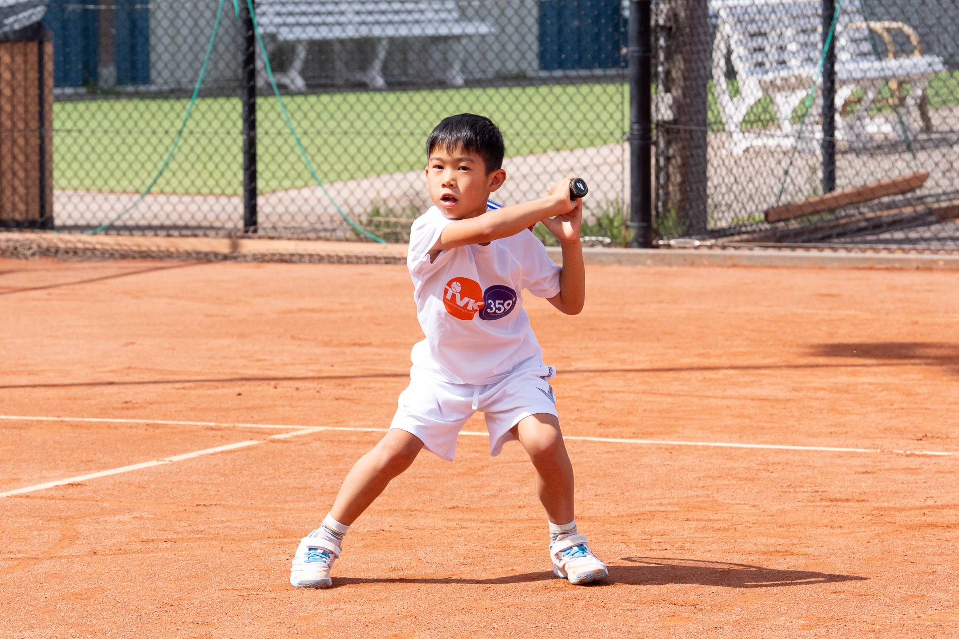 Jonge Academy speler in backhand-positie op gravel