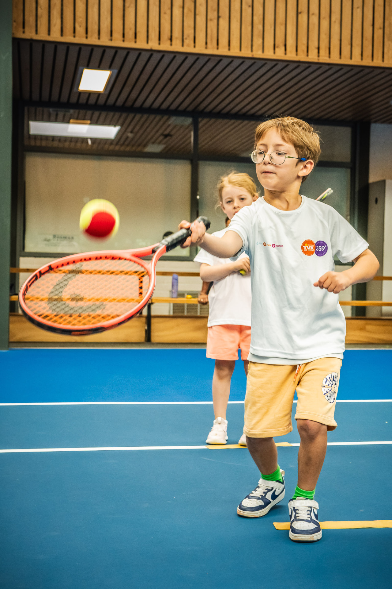 Kind slaat forehand met rode bal tijdens tennisles kinderen — 359.tennis