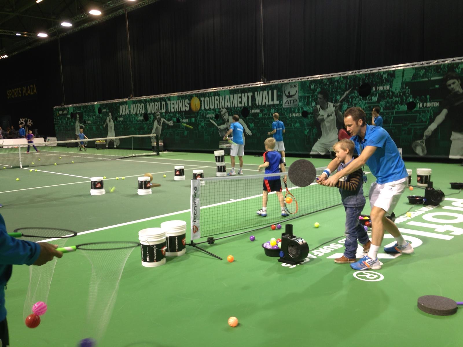 Roland Laurense helping a young child hit a floating ball during floater tennis at the ABN AMRO World Tennis Tournament
