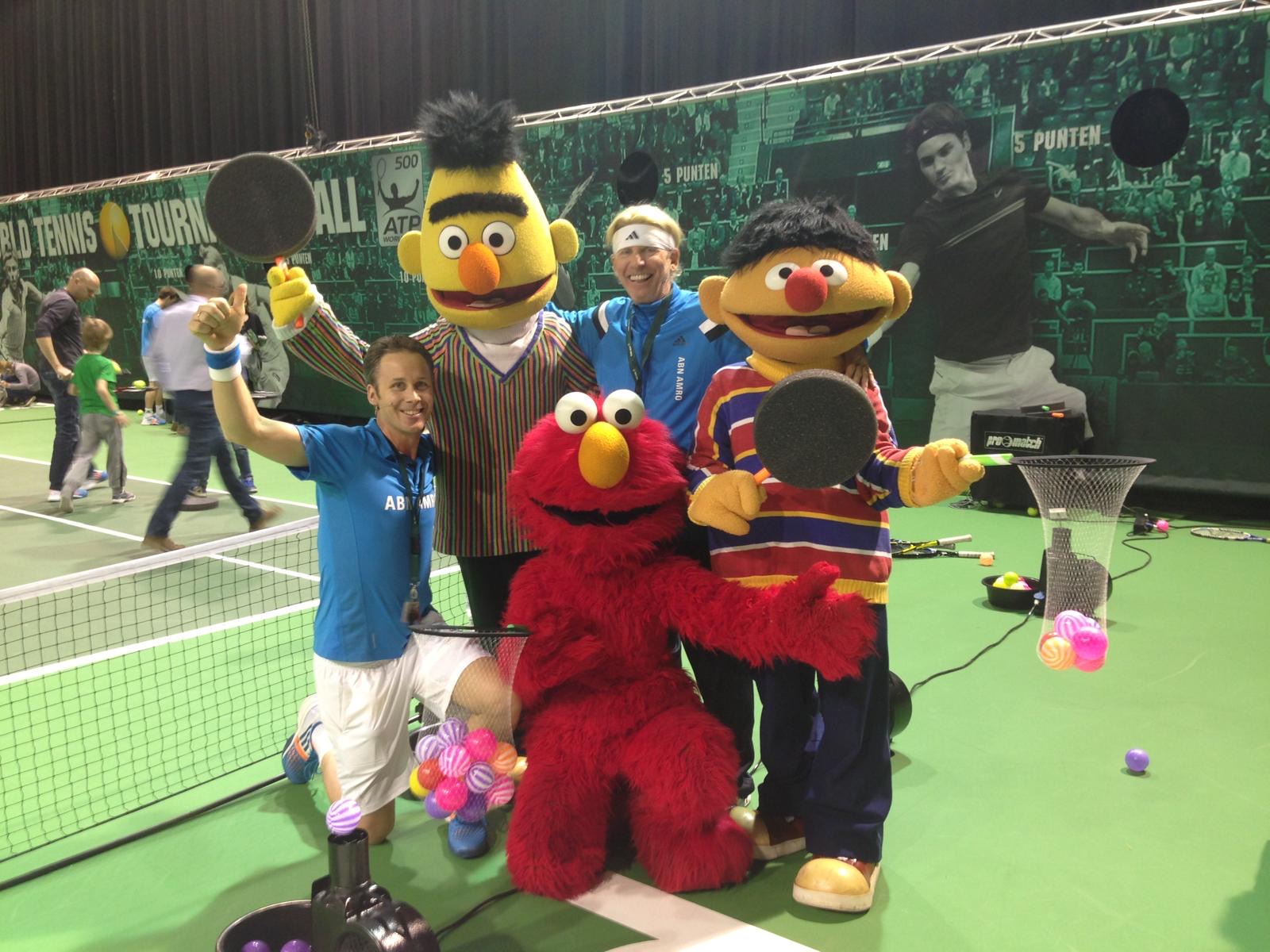 Roland Laurense with a tennis pro and Sesame Street mascots Bert, Ernie and Elmo on court at the ABN AMRO tournament