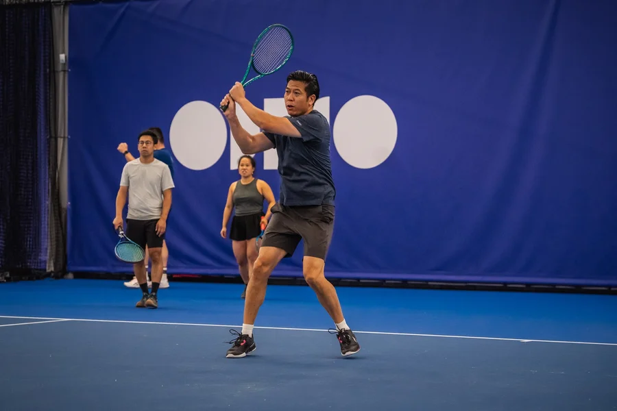 Speler slaat een backhand op de blauwe indoorbaan van het NTC Amstelveen tijdens het winterseizoen van 359.tennis